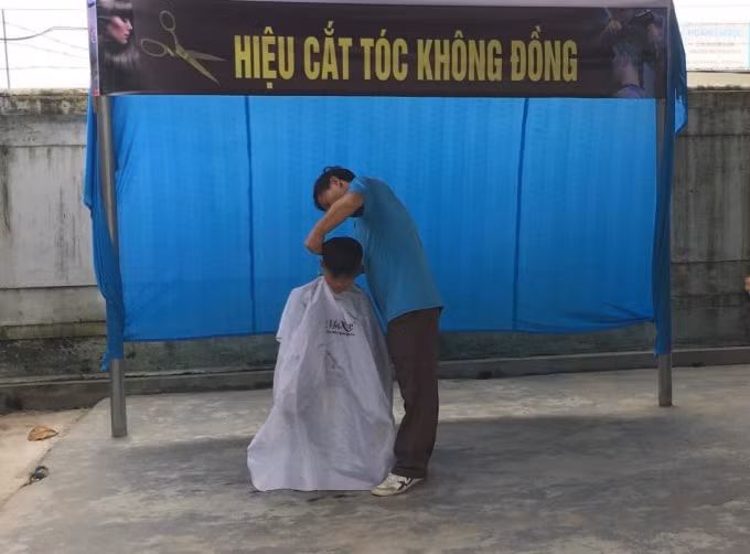 Thầy giáo đang chăm chú, tỉ mẩn hớt từng sợi tóc cho những cậu học trò của mình