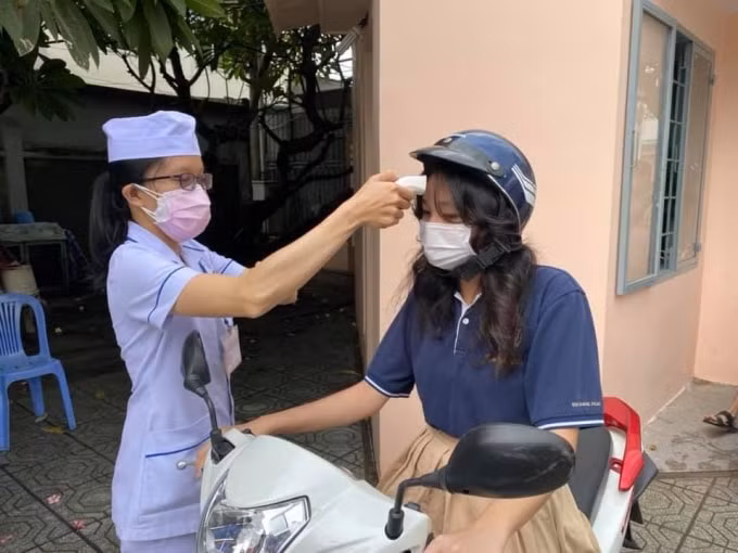 Kiểm tra sức khỏe, đo thân nhiệt các sĩ tử trước trước khi vào làm thủ tục tham gia kỳ thi tốt nghiệp THPT.