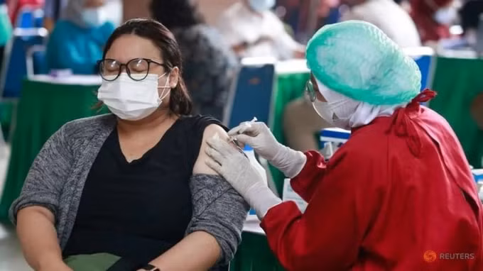 Một phụ nữ phản nhận một liều vắc-xin phòng bệnh coronavirus (COVID-19) trong chương trình tiêm chủng hàng loạt tại Trung tâm Chính quyền Thành phố Tangerang, ở Tangerang, ngoại ô Jakarta, Indonesia, ngày 30 tháng 6 năm 2021. @ REUTERS / Ajeng Dinar Ulfiana
