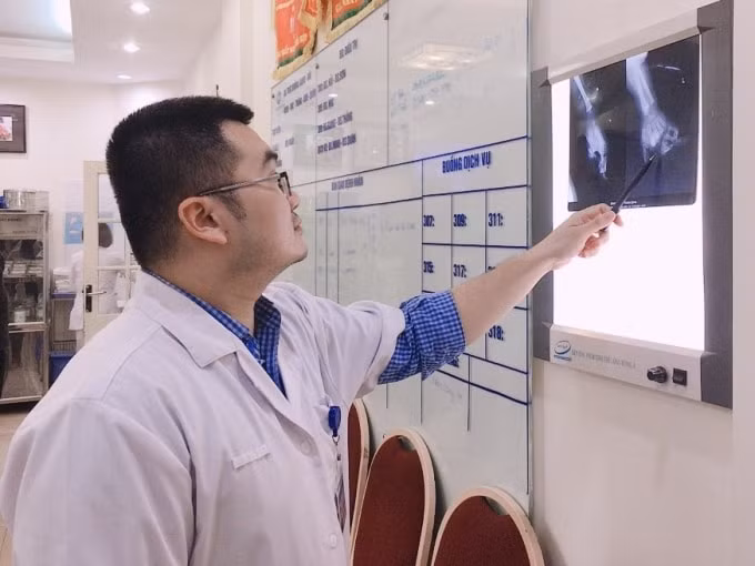 Bác sĩ Nguyễn Hoàng Quân, khoa Phẫu thuật Chi trên và Y học thể thao, Bệnh viện Hữu nghị Việt Đức kiểm tra phim chụp của bệnh nhân M (ảnh TL).