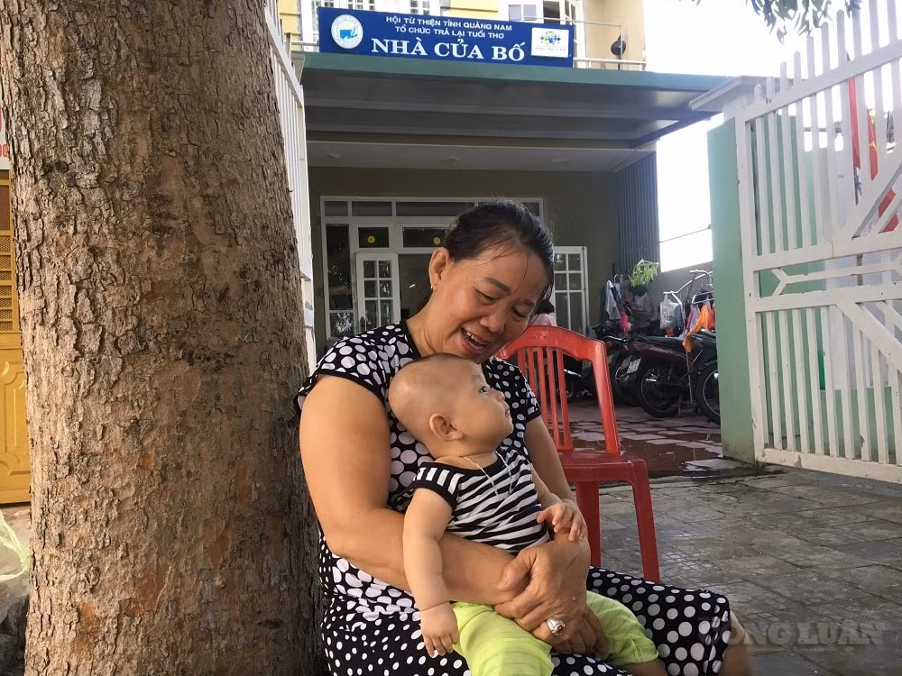 Bà Nguyễn Thị Mai bế em bé con của những bà mẹ trẻ đơn thân tại 