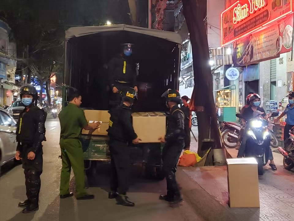 Lực lượng chức năng vận chuyển các thùng thuốc tây bị tạm giữ ra xe công vụ, phục vụ công tác điều tra. Ảnh: laodong.vn