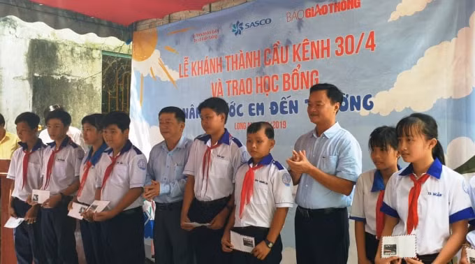 Ông Nguyễn Bá Kiên - Tổng biên tập Báo Giao thông và ông Nguyễn Quốc Trung, Phó giám đốc Sở GTVT tỉnh Long An trao 20 suất quà từ Quỹ chung tay vì ATGT của Báo Giao thông cho các em học sinh. Ảnh: baoggiaothong.vn