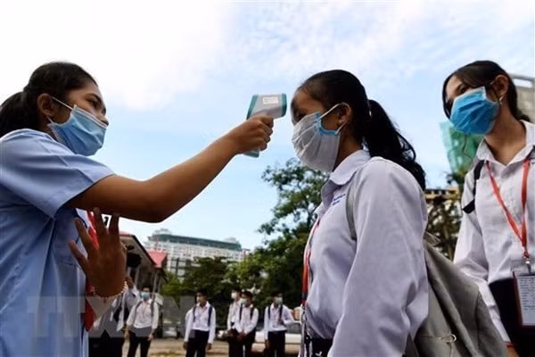 Học sinh tại Campuchia thực hiện kiểm tra đo thân nhiệt. Ảnh: TTXVN