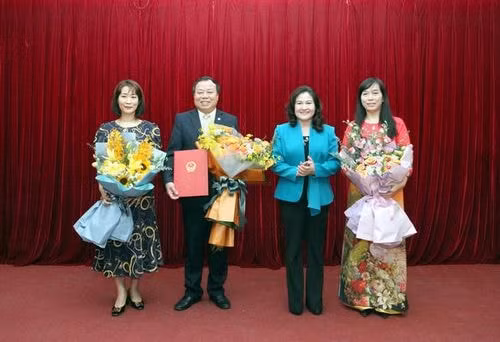 Thứ trưởng Nguyễn Thị Hà trao quyết định sáp nhập Tạp chí Gia đình và Trẻ em vào Báo Lao động và Xã hội và tặng hoa Ban biên tập Báo. Ảnh: Nguyễn Síu