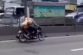 Người đàn ông lái xe máy chạy trên đường, mặc cho CSGT bám yên xe