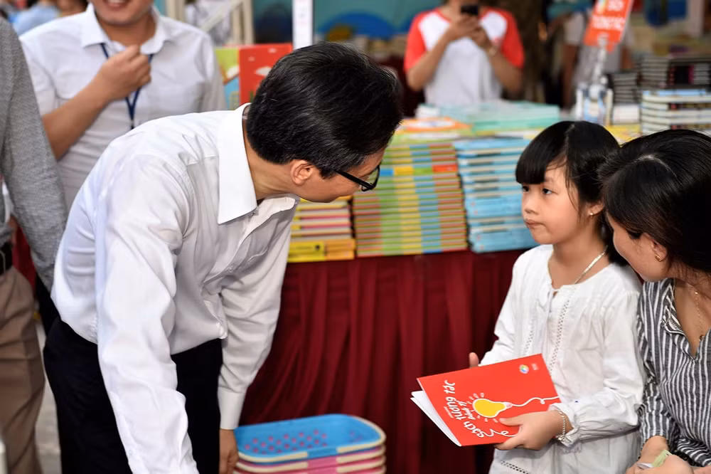 Phó Thủ tướng Vũ Đức Đam hỏi chuyện một cháu nhỏ 6 tuổi đang cầm cuốn Sách tương tác. Ảnh: VGP