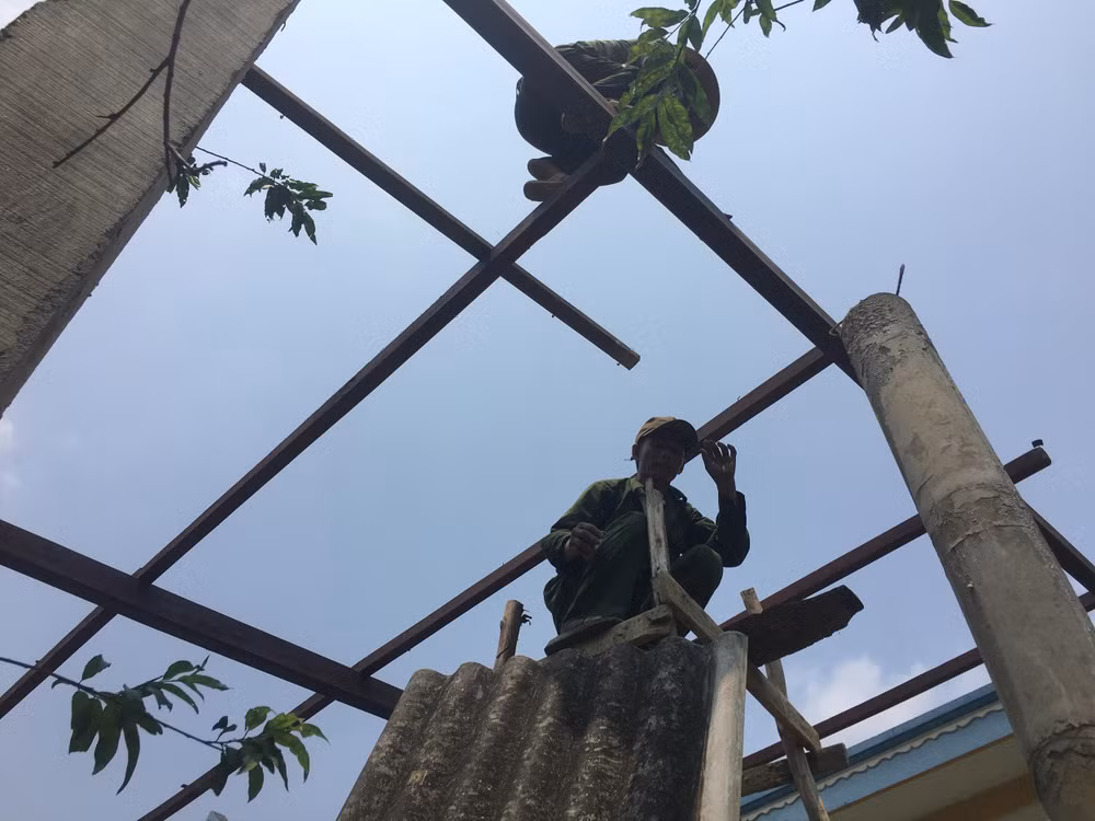 Người dân lợp lại mái nhà sau khi bị trận lốc thổi bay.