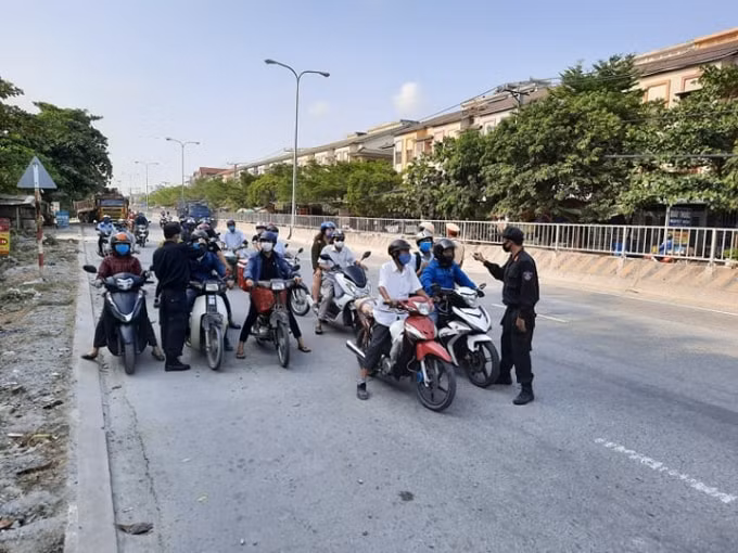 Lực lượng công an Đồng Nai đo thân nhiệt người dân tại tuyến đường Quốc lộ 1K -ảnh: N/T