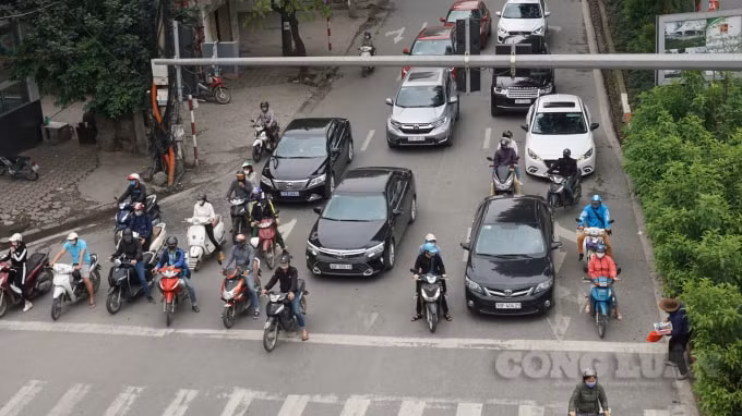 Người dân đứng chờ đèn đỏ tại ngã tư đường Láng giao với đường Lê Văn Lương. Ảnh H.Long.