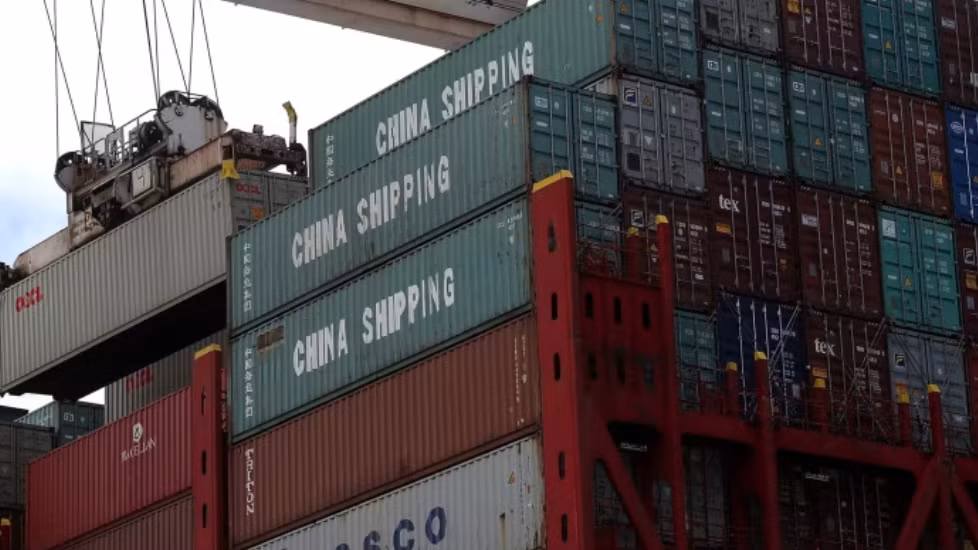 Cần cẩu đang bốc dỡ container mang nhãn "CHINA SHIPPING" từ tàu hàng. Ảnh: Financial Times