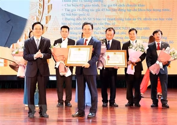 Thừa ủy quyền của Chủ tịch nước, Bộ trưởng Bộ Giáo dục và Đào tạo Phùng Xuân Nhạ trao Huân chương Lao động hạng Ba cho các tập thể, cá nhân của trường. Ảnh: TTXVN