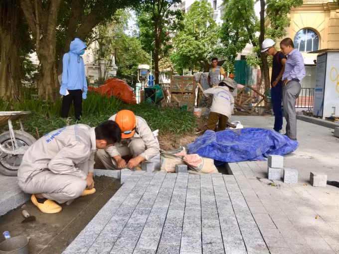 Các công nhân thực hiện công việc ốp lát, từng viên đá sẽ được đặt xen kẽ nhau và được kết dính bằng xi măng. Ảnh: Thu Hà
