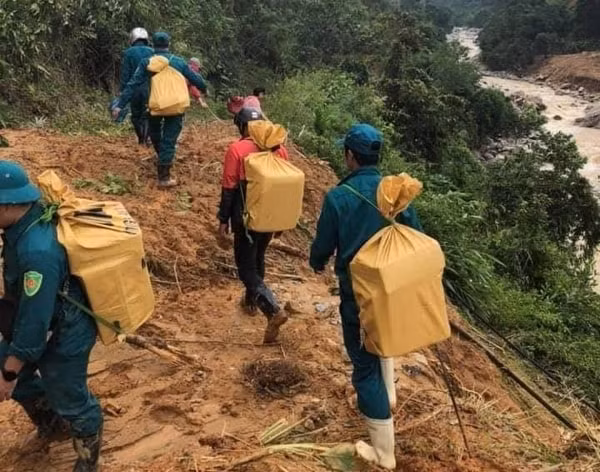 Lực lượng dân quân địa phương gùi lương thực, thực phẩm tiếp tế đến người dân xã Phước Thành