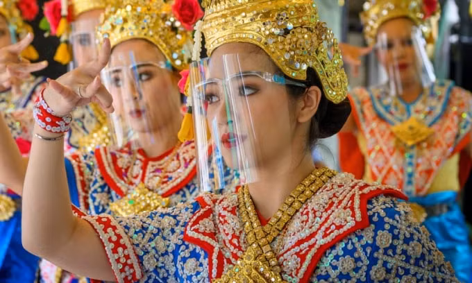Các vũ công truyền thống Thái Lan đeo tấm chắn ngăn giọt bắn khi biểu diễn tại đền thờ Erawan ở Bangkok. (Nguồn: AFP)
