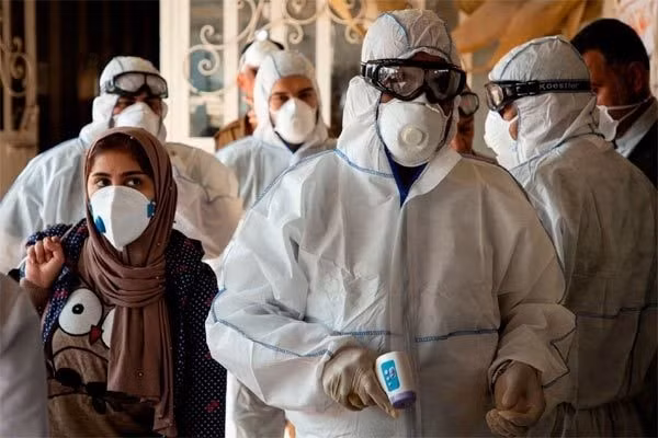 Các nhân viên y tế Iran đo nhiệt độ cho người qua lại khu vực biên giới.Ảnh: New York Times.