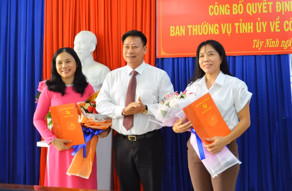 Phó Bí thư Tỉnh uỷ Nguyễn Thanh Ngọc tặng hoa, trao quyết định cho bà Trần Thị Mỹ Linh và bà Huỳnh Thanh Nam (bên phải). Ảnh Đức An