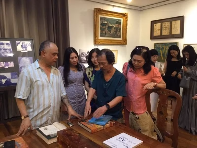 Họa sĩ Bùi Thanh Phương (áo xanh), con trai họa sĩ Bùi Xuân Phái trao một số kỷ vật của cố họa sĩ cho nhà sưu tập Trần Hậu Tuấn