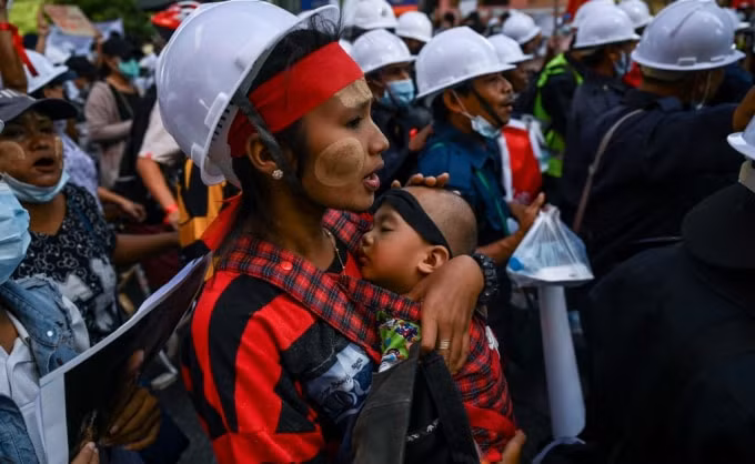 Một người biểu tình bế một đứa trẻ khi cô tuần hành với hàng nghìn người biểu tình ở Yangon vào thứ Tư (10/2), khi họ tiếp tục bất chấp cảnh báo của chính quyền quân sự - Ảnh: Ye Aung Thu / AFP