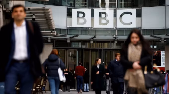 Người đi bộ đi ngang qua logo của BBC tại Broadcasting House ở London. Đài truyền hình dịch vụ công cộng đã bị chặn ở Trung Quốc. © Reuters