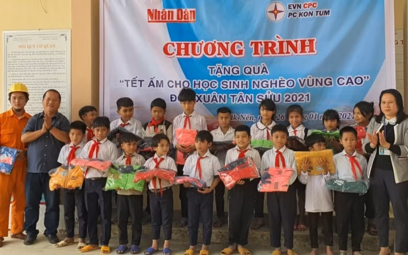 Phóng viên Báo Nhân Dân cùng đại diện Công ty Điện lực Kon Tum trao áo ấm cho các em học sinh Trường PTDT bán trú tiểu học Đắk Nên. Ảnh: Phúc Thắng