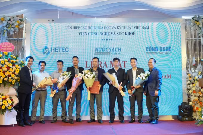 Ông Lê Hữu Thi - Viện trưởng Viện công nghệ và Sức khỏe (ngoài cùng bên trái) và ông Vương Văn Việt&nbsp; - Tổng Biên tập Tạp chí Sức khỏe Cộng đồng trao quyết định và tặng hoa chúc mừng các thành viên Ban Quản lý DA Nước sạch học đường Việt Nam.