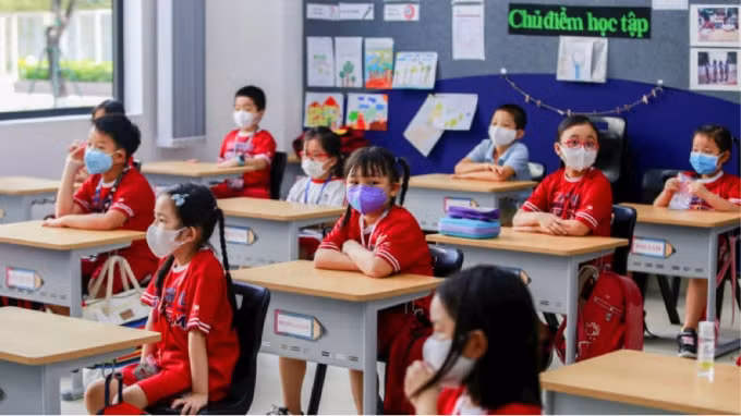 Học sinh tiểu học Việt Nam đeo khẩu trang bảo vệ vào ngày đầu tiên đến lớp sau khi chính phủ nới lỏng lệnh cấm vận trên toàn quốc vào tháng 5 năm 2020. Ảnh: Reuters