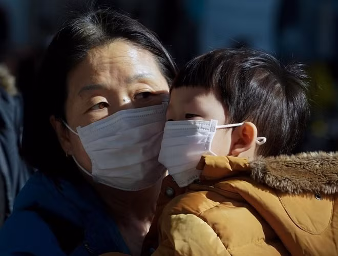 Một người mẹ và đứa con đeo khẩu trang để tránh tiếp xúc với loại virus corona mới ở Seoul, Hàn Quốc, ngày 26/1. Ảnh: Yonhap/Reuters.