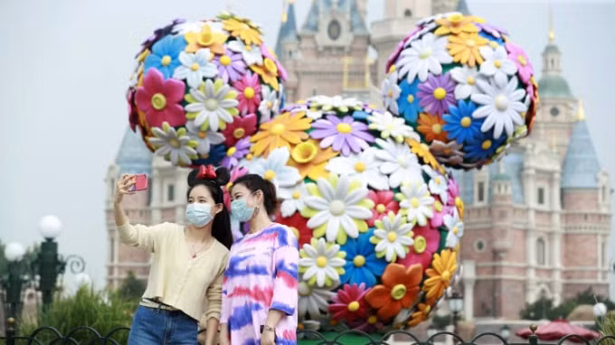 Du khách đeo mặt nạ chụp ảnh tự sướng tại Khu nghỉ dưỡng Disney Thượng Hải ngày 11 /5 tại Thượng Hải, Trung Quốc. Ảnh: Getty