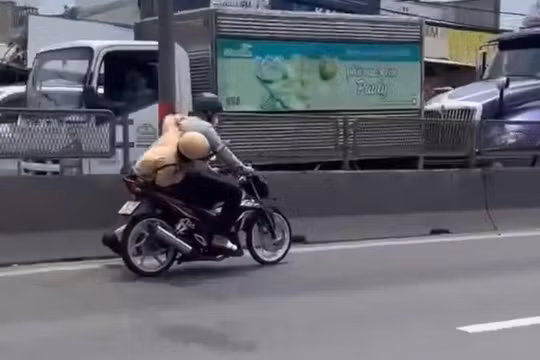 Người đàn ông lái xe máy chạy trên đường, mặc cho CSGT bám yên xe