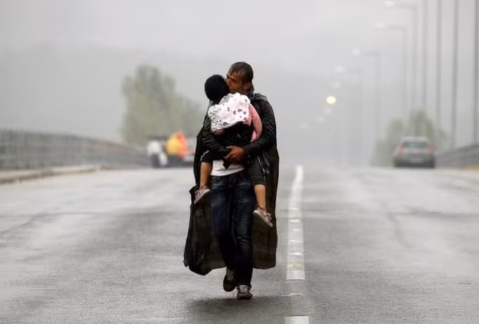 Một người di cư hôn con gái mình khi đi bộ tới biên giới giữa Hy Lạp và Macedonia,10/09/2015. Ảnh: Reuters