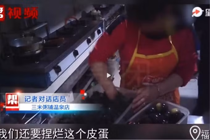 Một nhân viên bếp tại một nhà hàng cháo Man Lin “bới” thức ăn thừa từ những bát cháo đã qua sử dụng để nấu lại cho khách hàng khác.