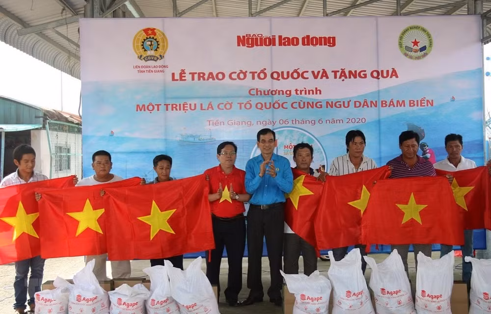 Chủ tịch Liên đoàn lao động tỉnh Tiền Giang Trương Văn Hiền và Tổng Biên tập Báo Người Lao động Tô Đình Tuân trao quà và cờ Tổ quốc cho các ngư dân.