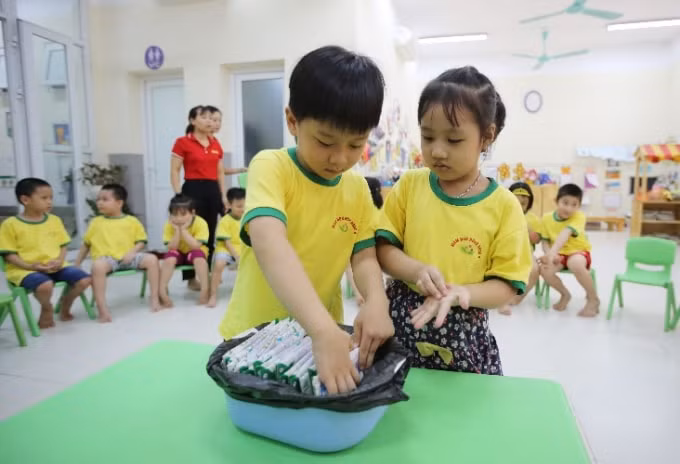 Các em học sinh được hướng dẫn cách gấp gọn và thu dọn hộp sữa sau khi sử dụng xong