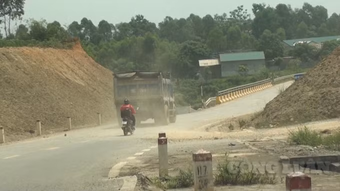 Những xe tải chở đất đi qua để lại phía sau làn bụi dày đặc.