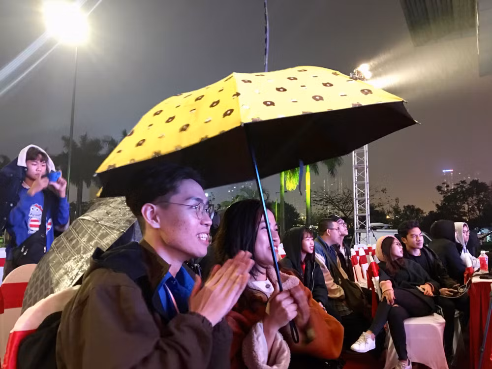 Mặc dù trời mưa và lạnh nhưng không khí tại sự kiện vẫn náo nhiệt, các bạn sinh viên vẫn hào hứng thưởng thức và cổ vũ cho các tiết mục trình diễn trên sân khấu. Ảnh: Huy Hoàng