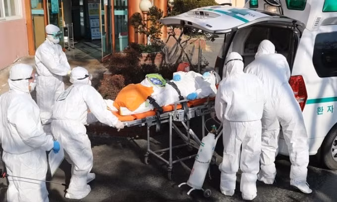 Nhân viên y tế đưa người nghi nhiễm Covid-19 vào bệnh viện ở Hàn Quốc ngày 21/2. Ảnh: AFP.