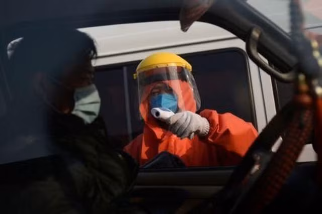Một nhân viên kiểm tra thân nhiệt của các tài xế tại Bắc Kinh, Trung Quốc. Ảnh: Reuters