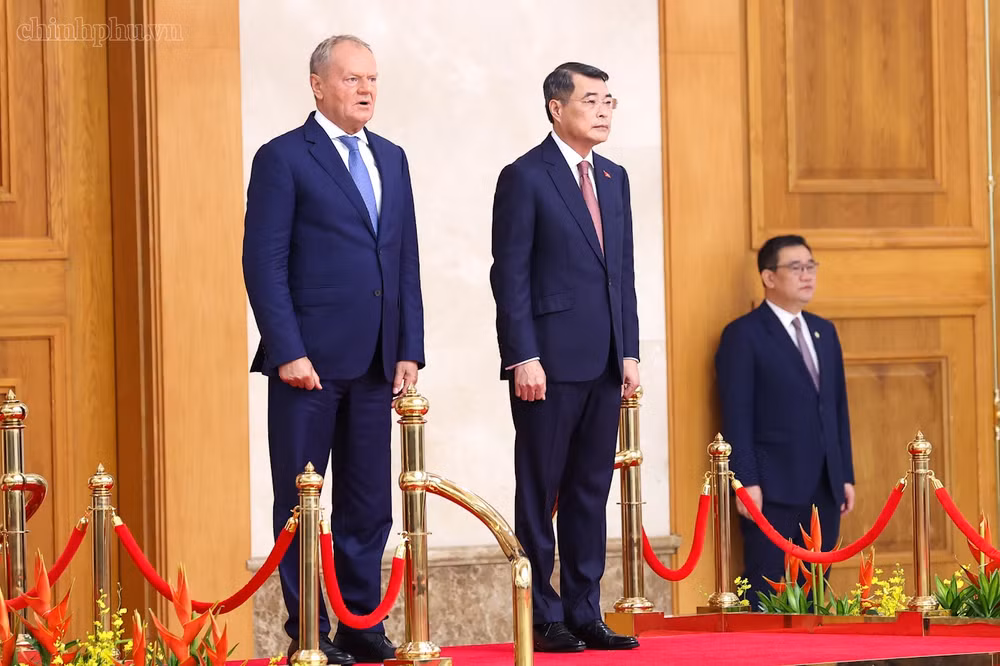 Thủ tướng Lê Minh Hưng và Thủ tướng Donald Tusk trên bục danh dự nghe Quân nhạc cử Quốc thiều hai nước. Ảnh: CP