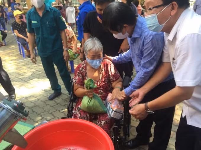 Chủ tịch Hội Nhà báo TP.HCM Trần Trọng Dũng (áo xanh) thăm hỏi, hỗ trợ người lớn tuổi đến nhận gạo vào sáng khai trương máy 