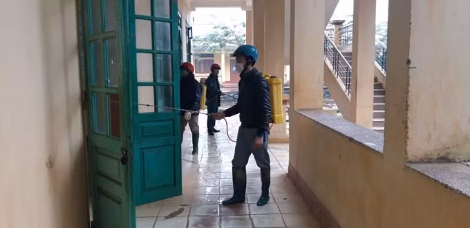 Cơ quan chức năng huyện Chiêm Hóa (Tuyên Quang) phun khử trùng bàn ghế, sàn nhà, các cánh cửa, lan can hành lang tại trường THPT Hà Lang. Ảnh Đoàn Cường.