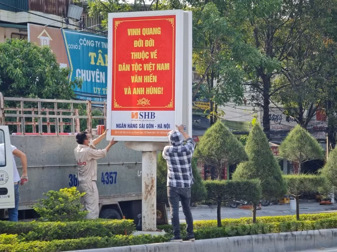 Các công nhân gấp rút đặt các pa nô, áp phích, treo băng rôn ở những tuyến đường chính