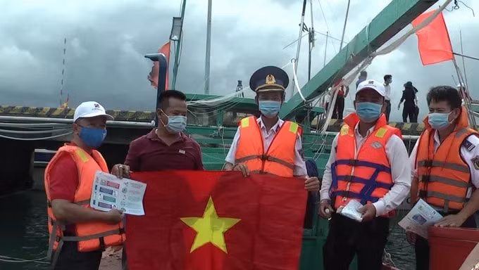 Trao cờ Tổ quốc, khẩu trang y tế và tuyên truyền pháp luật cho ngư dân. Ảnh: NLĐO