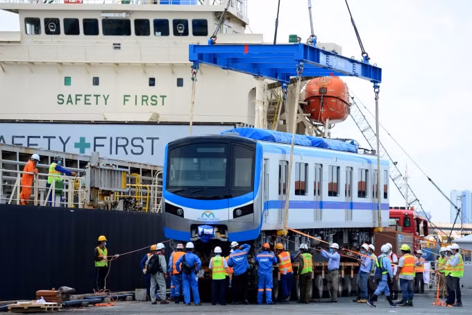 Các kỹ sư, công nhân dùng cẩu tàu có chiều dài 32 m, sức nâng hơn 30 tấn để nâng hạ toa tàu xuống rơ-moóc của xe siêu trường, siêu trọng.