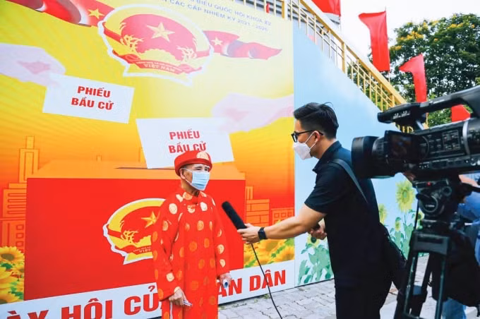 Phóng viên Trần Mộng Long phỏng vấn cử tri trong ngày bầu cử.