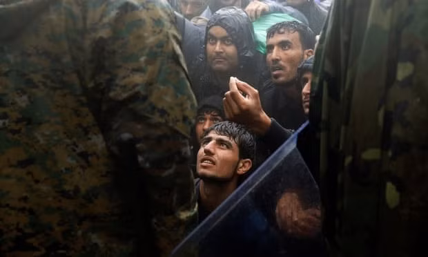 Những người nhập cư cầu xin cảnh sát Macedonia cho họ nhập cảnh. Ảnh: Reuters