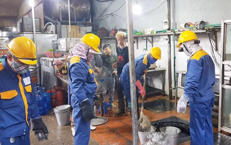 Công nhân Công ty TNHH MTV Thoát nước Hà Nội thu gom dầu mỡ đóng cặn tại thiết bị tách sau thời gian lắp thử nghiệm tại nhà hàng. Ảnh: TL