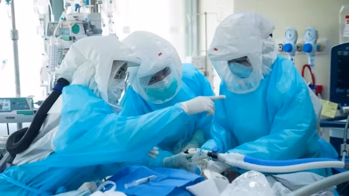 Một bác sĩ và y tá đeo thiết bị bảo vệ cá nhân (PPE) điều trị cho một bệnh nhân bị COVID-19 tại Đơn vị Chăm sóc Đặc biệt tại Bệnh viện King Chulalongkorn Memorial ở Bangkok. © Reuters