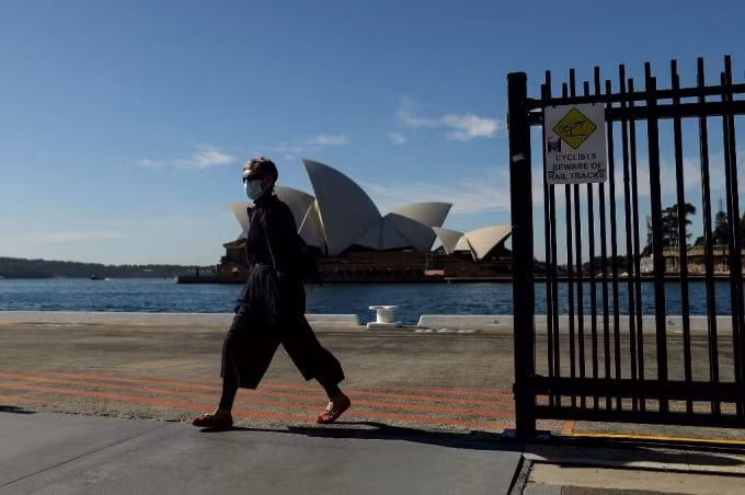 Một người đi bộ đeo khẩu trang đi ngang qua Nhà hát Opera Sydney ở Sydney vào ngày 13/7, trong khi các nhà chức trách tăng cường nỗ lực kiềm chế đợt bùng phát COVID-19 - Ảnh: AFP