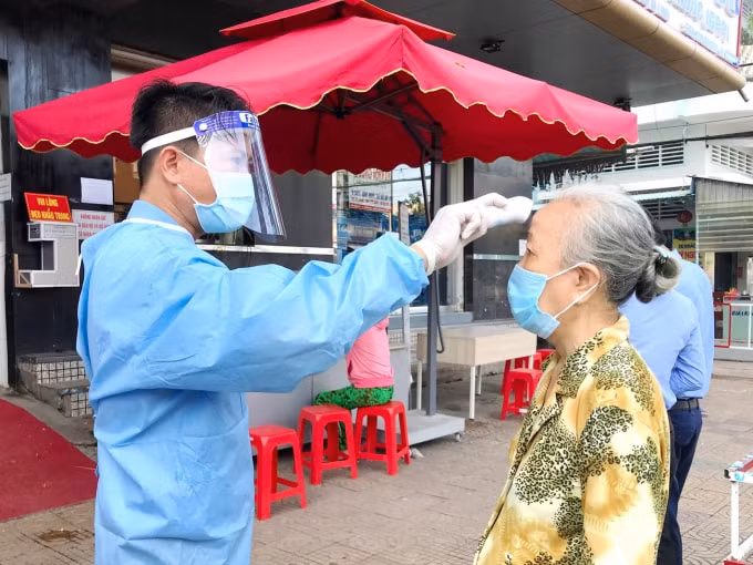 Nhân viên bệnh viện thực hiện đo thân nhiệt, sát khuẩn cho người dân đến khám chữa bệnh.